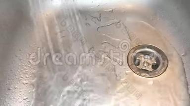 <strong>厨房不锈钢水槽</strong>中的水喷到金属排水沟上。 水龙头里的水充满了<strong>水槽</strong>。